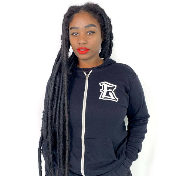 Woman wearing black Elevate E Zip Up Sweatshirt with side-seamed retail fit and ribbed cuffs, made from 100% Airlume ring-spun cotton.