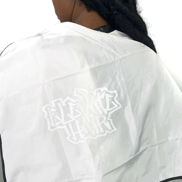 Elevate Hair white cape with logo on back neckline, button neck closure, worn by model with braided hair