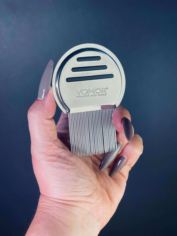 VoMor Tape In Removal Comb, stainless steel extra-fine tooth comb, ideal for removing hair extensions, held in a hand against a dark background.