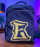E Stylist Barber Backpack with large "E" logo on wooden table, featuring adjustable straps and multiple pockets.