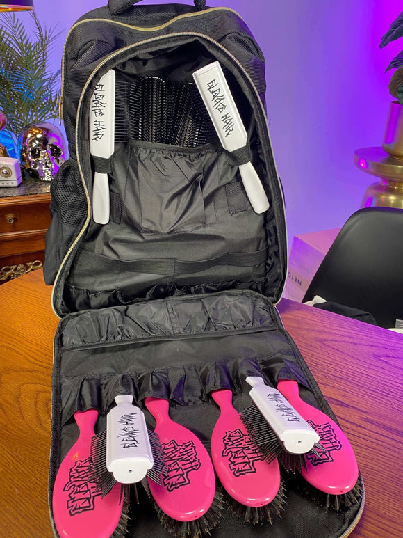 E Stylist Barber Backpack with open compartments showing various brushes inside, placed on a wooden table.